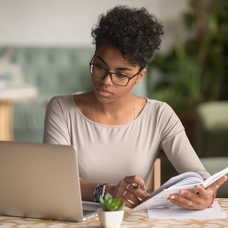 elearning Woman using a computer and fliping through a workbook