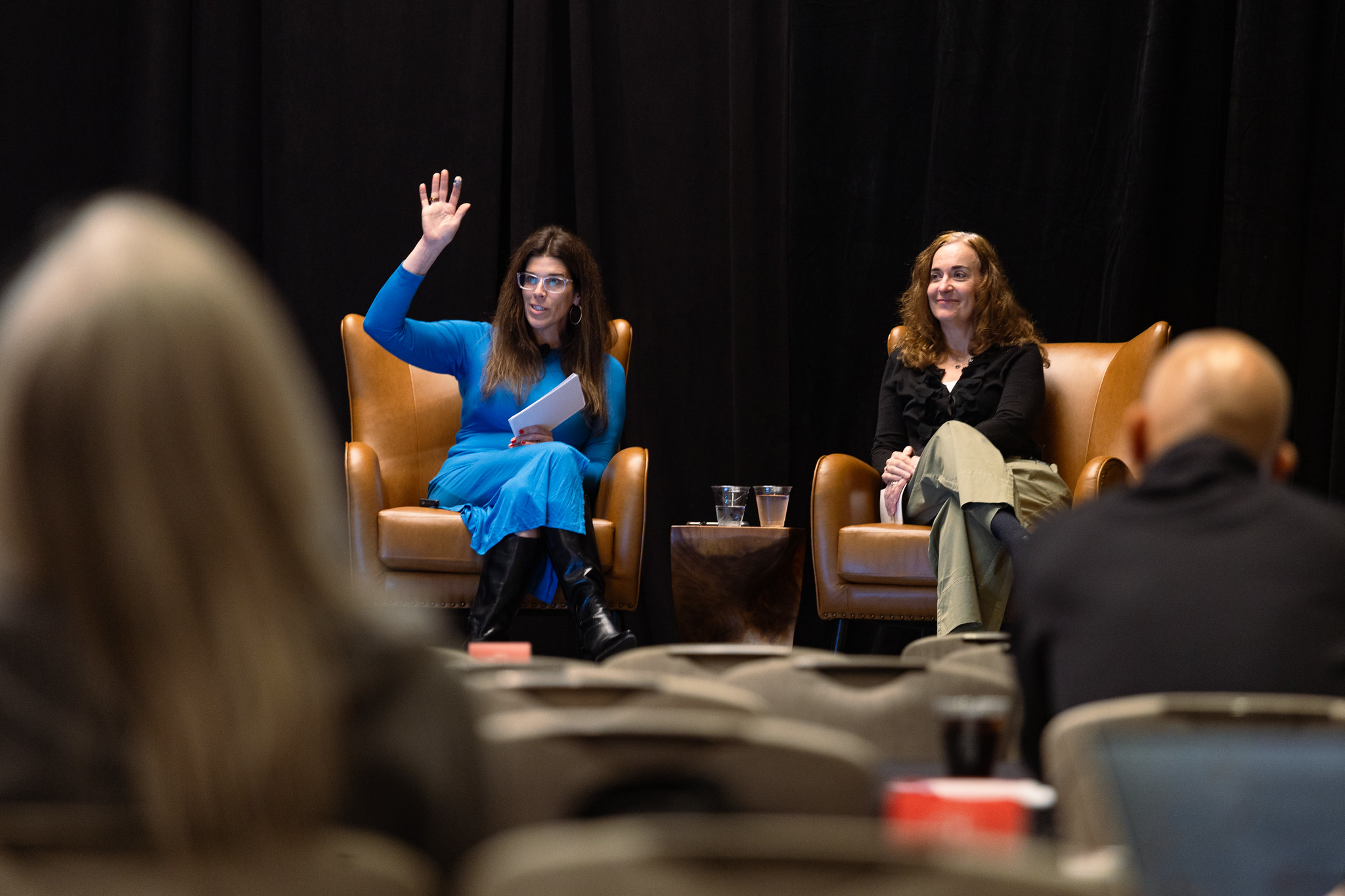 Two women sit in chairs during their presentation at DEAMcon26.
