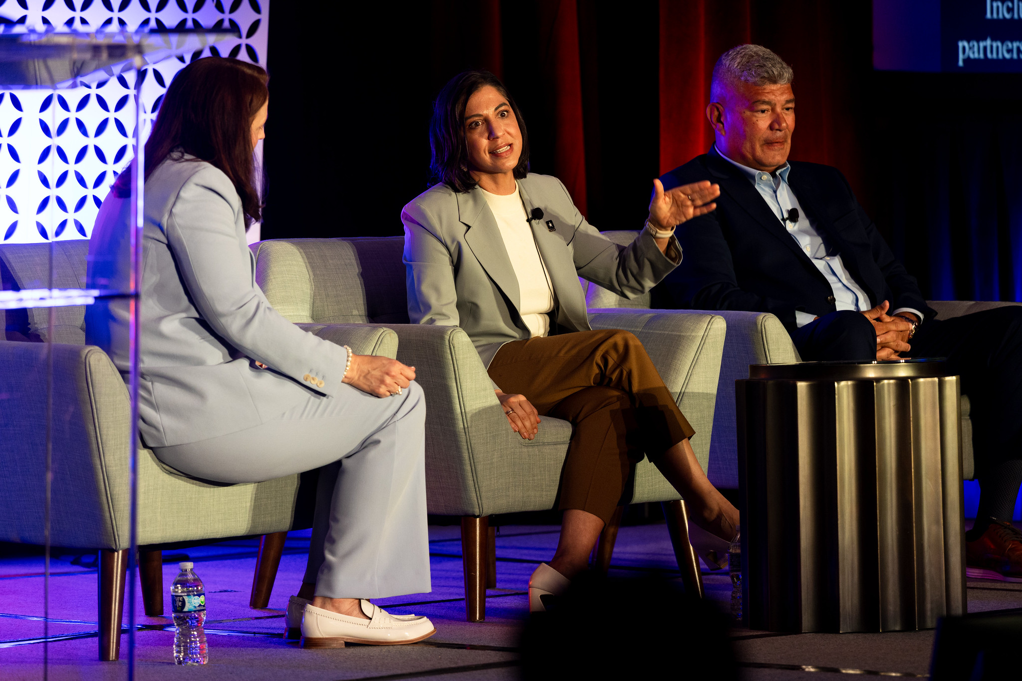 Two women and a man sit on the DEAMcon stage during their session.