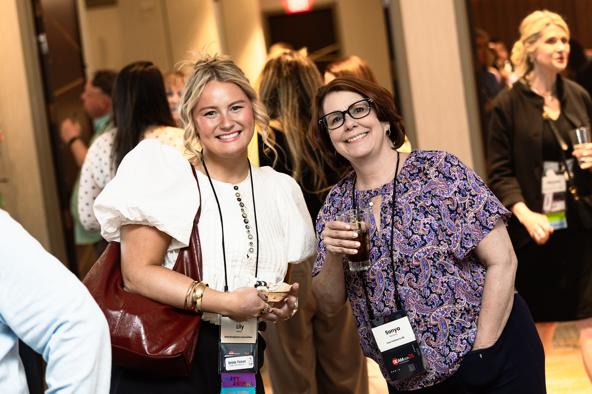 Two women smile for a photo during a reception during DEAMcon26.