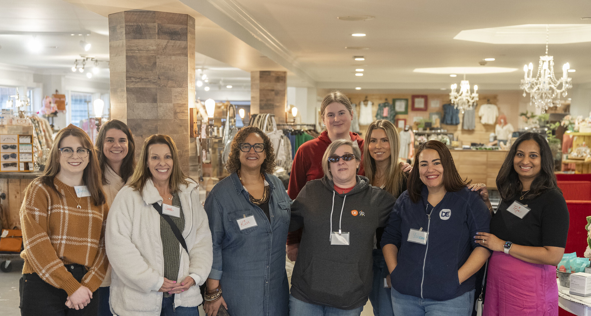 A group of women pose for a photo in a store-like setting.